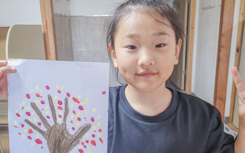 부스 활동에서 그린 그림을 들고 웃는 참가자